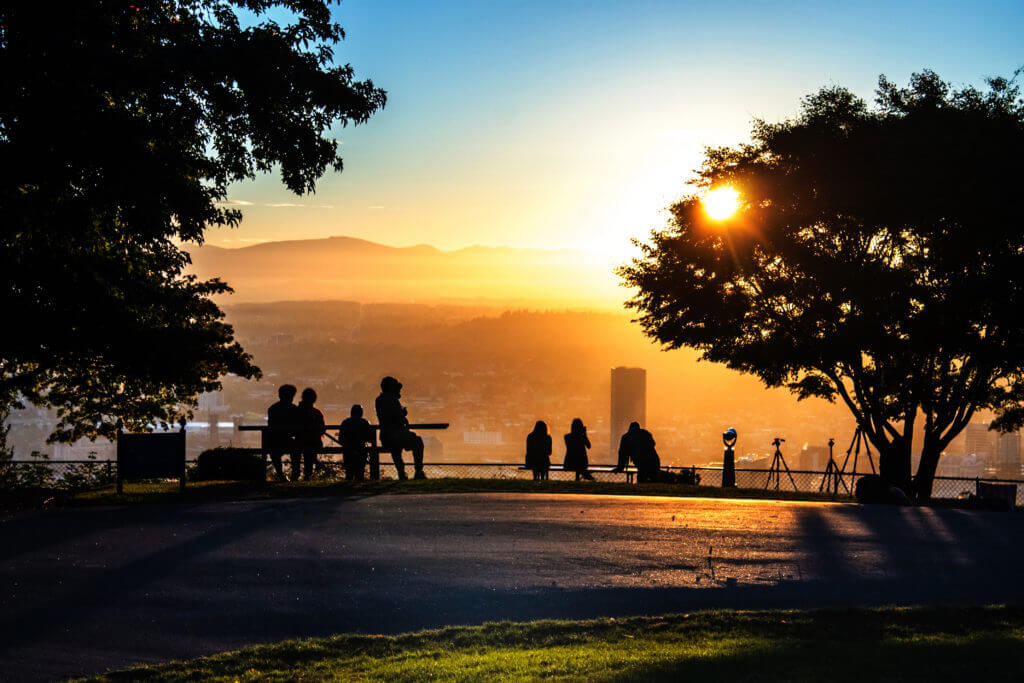 Early morning sightseers and photographers gather together on the overlook at Pittock Mansion west of Portland, Oregon. The building dubbed "Big Pink" stands tall as the first rays of daylight warm the waking city.